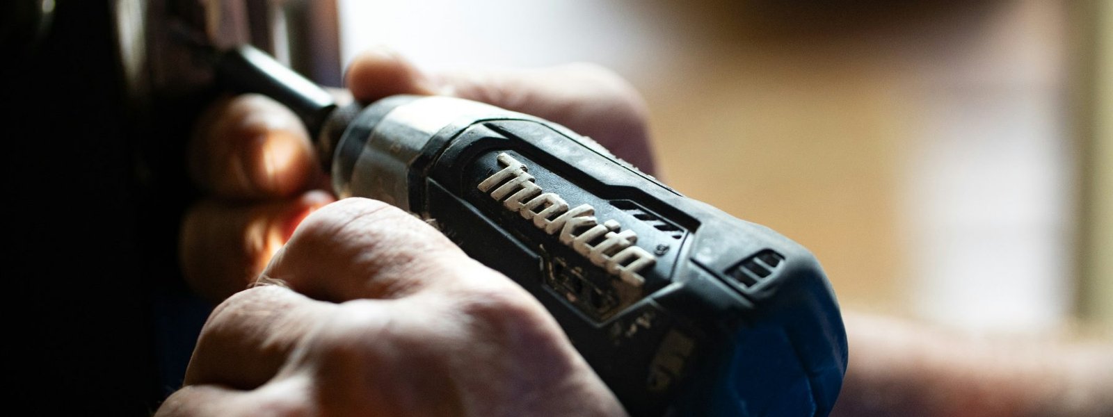 Cordless drill held against the edge of a door while security hardware is installed