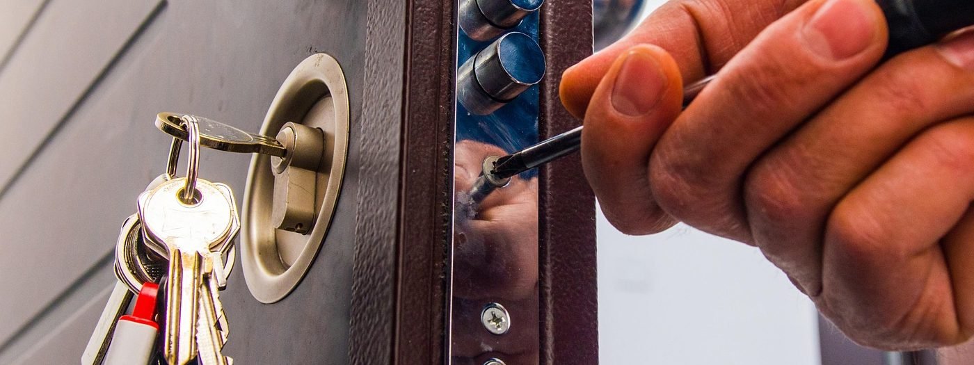 Keys hanging from the cylinder of a security door while a screwdriver is used on the multi point lock