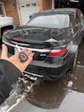 Locksmith holding a new car key fob behind a black sedan