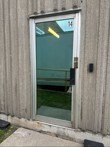 Commercial glass entry door with new lock hardware on a wood clad building