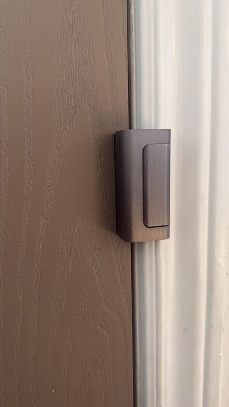 Bronze door security latch mounted on the frame of a brown door