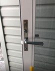 Black lever handle and deadbolt installed on a grey exterior door