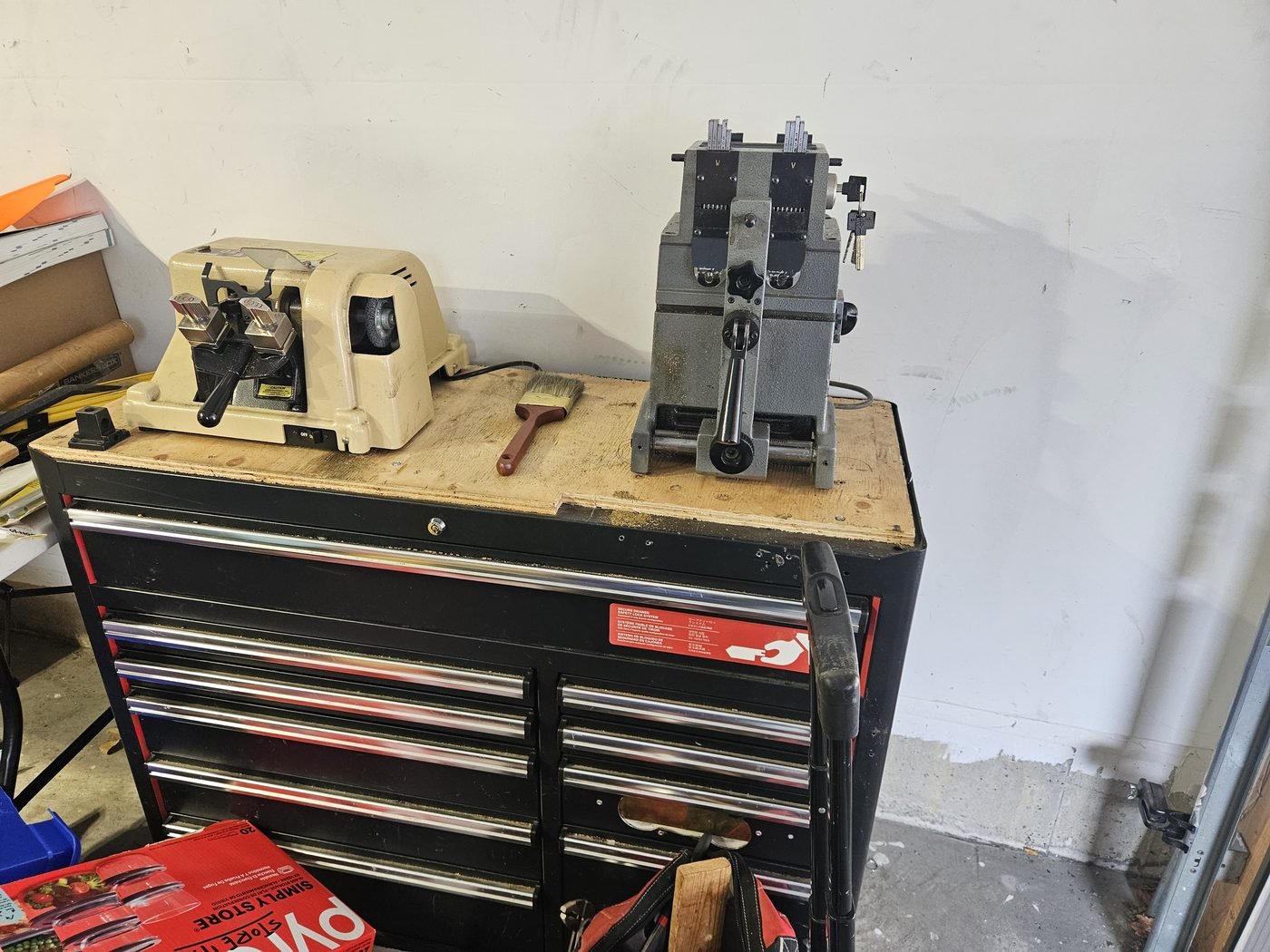 Two key cutting machines on the workbench in the Woodbridge Locksmith shop, above a red tool chest