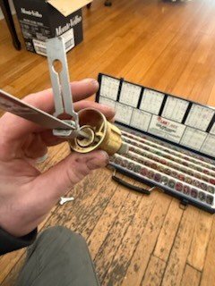 Brass cylinder being rekeyed on site next to an open pinning kit
