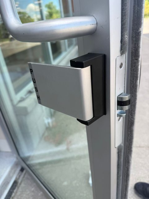 Latch guard installed on an aluminum and glass storefront door